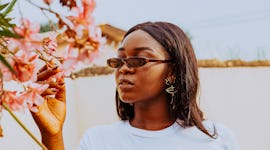 Young woman posing outdoors in sunglasses the week of March 7, 2022 before reading her weekly horosc...