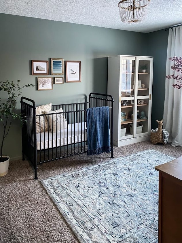 a neutral nursery with sage green walls and gallery art