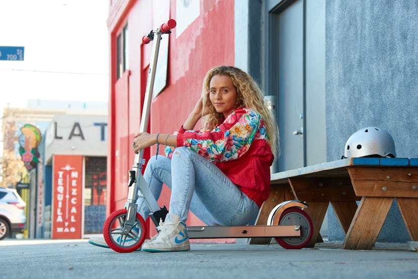 A millennial woman sits on the new razor Icon, an electric version of your nostalgic razor scooter.