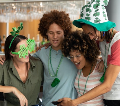 A group of friends celebrating St. Patrick's Day look at a St. Patrick’s Day meme and share St. Patr...