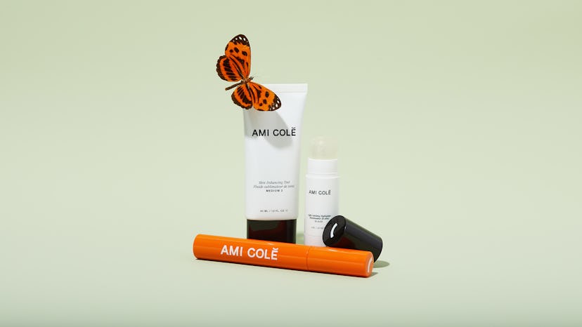 Ami Colé beauty product white tubes and an orange stick