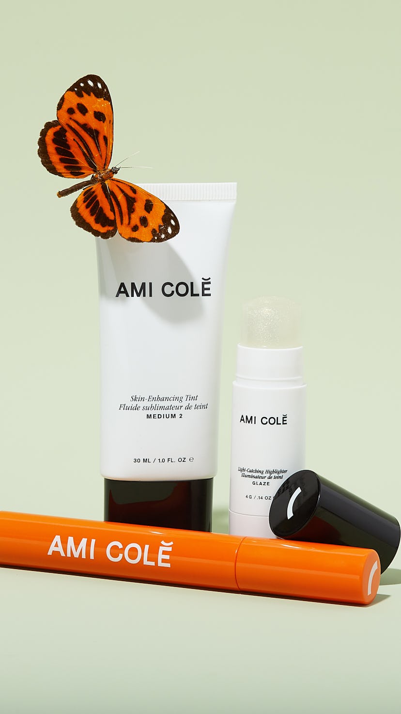 Ami Colé beauty product white tubes and an orange stick