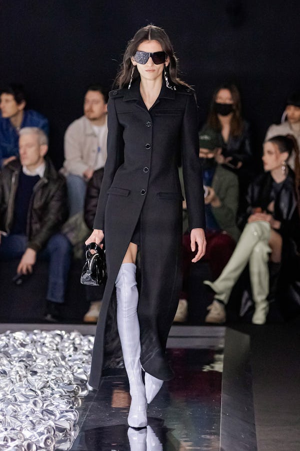 a model wearing a tailored black duster coat on the Courrèges runway