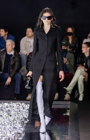 a model wearing a tailored black duster coat on the Courrèges runway