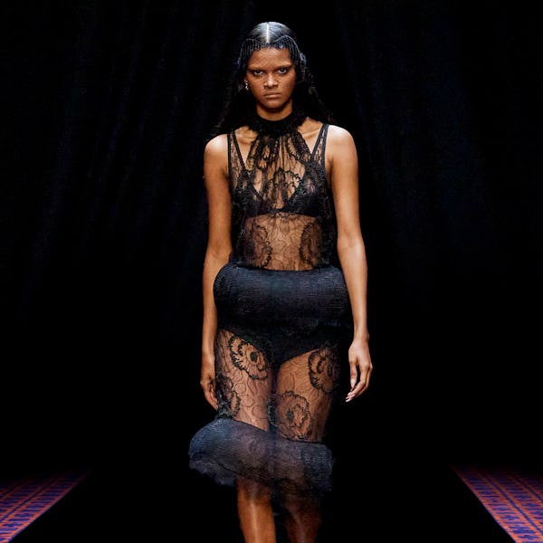 a model wearing a sheer black lace dress on the Lanvin runway