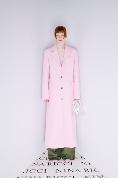 a model wearing a pastel pink duster coat by Nina Ricci