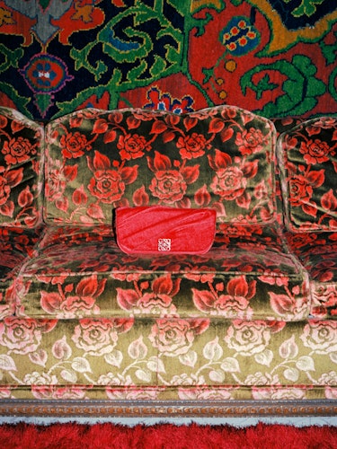 Red bag on floral sofa.
