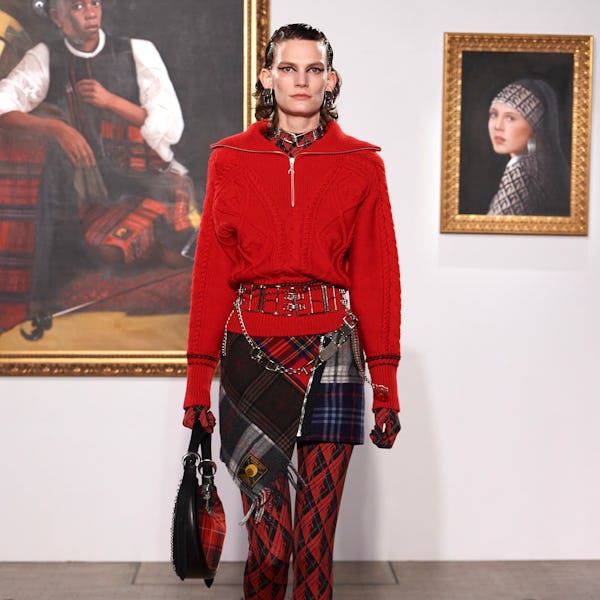 a model wearing a red half-zip sweater and mixed-print plaid miniskirt on the Marine Serre runway
