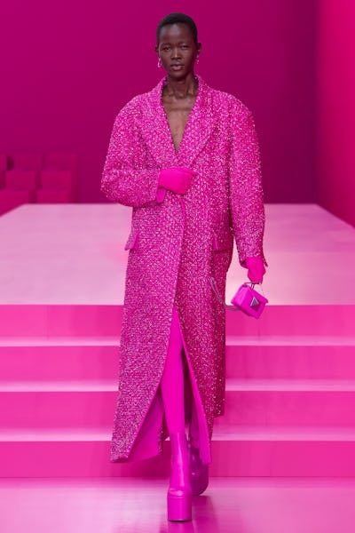 a model wearing a hot pink duster coat on the Valentino runway