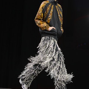 a model wearing silver fringe pants and a windbreaker on the Celine runway