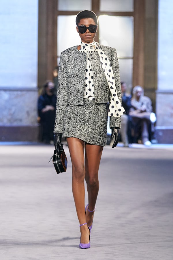 a model wearing a grey tweed skirt suit on the Ami runway