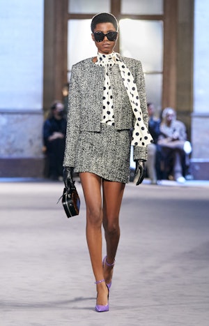 a model wearing a grey tweed skirt suit on the Ami runway