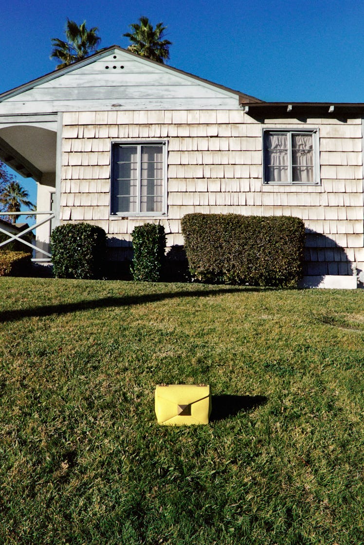 Yellow bag in grass in front of house.