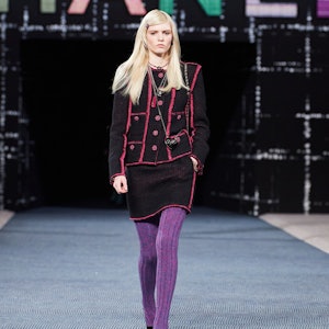 a model wearing a black tweed skirt suit with pink piping on the Chanel runway