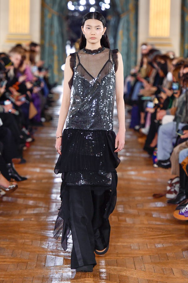 a model sheer black and silver sequin dress over black trousers on the Sacai runway