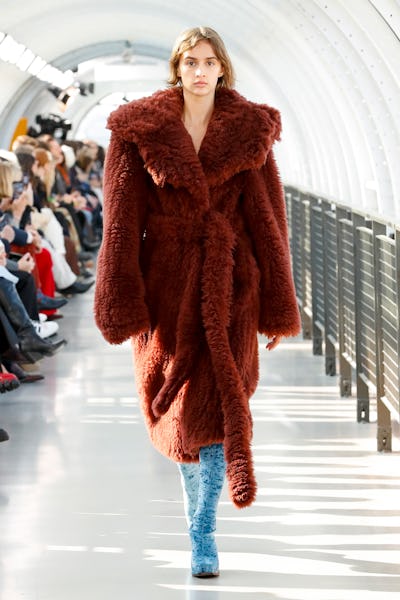 a model wearing a plush burgundy coat on the Stella McCartney Runway