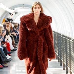 a model wearing a plush burgundy coat on the Stella McCartney Runway