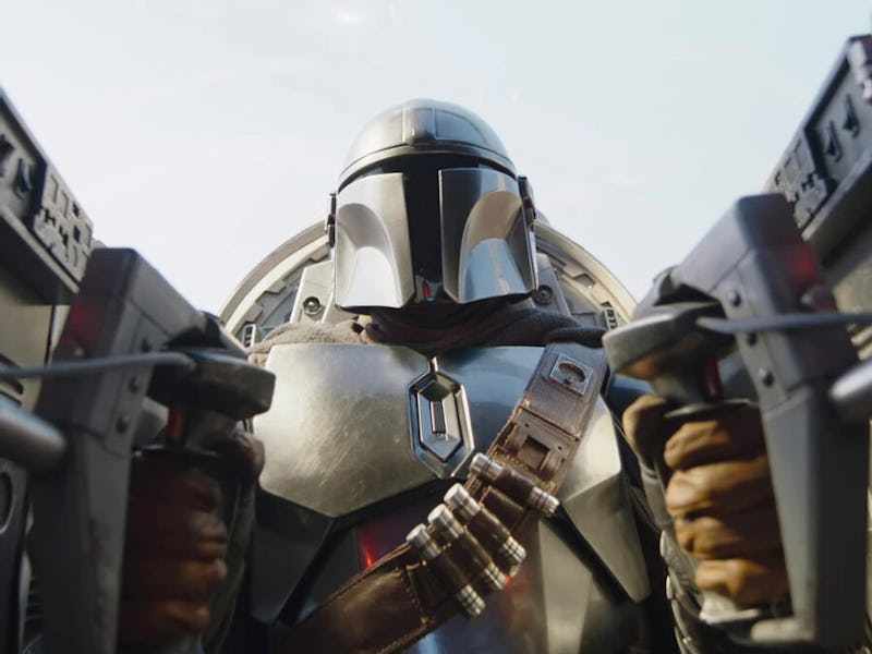 Pedro Pascal as Din Djarin in the Mandalorian series holding two guns