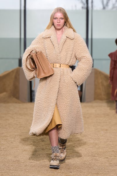 a model wearing an oversize shearling tan coat on the Chloé runway