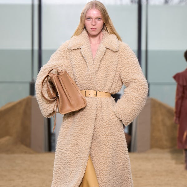a model wearing an oversize shearling tan coat on the Chloé runway