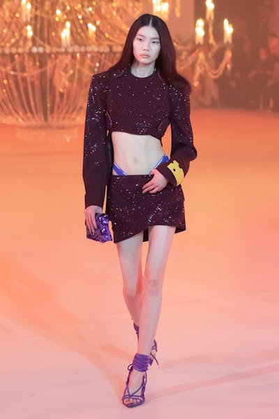 a model wearing a black cropped jacket and mini skirt on the Off-White runway