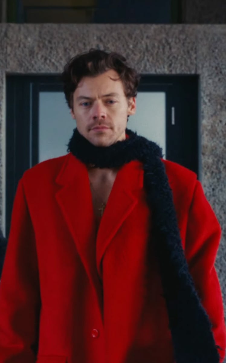 Harry Styles wore a red pea coat and black, feather boa at the open of his "As It Was" music video.