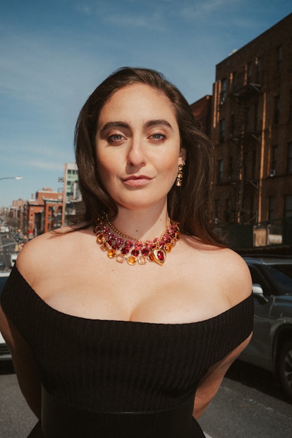 Catherine Cohen posing on the street wears a Michael Kors dress and belt, Mondo Mondo necklace; Rebe...