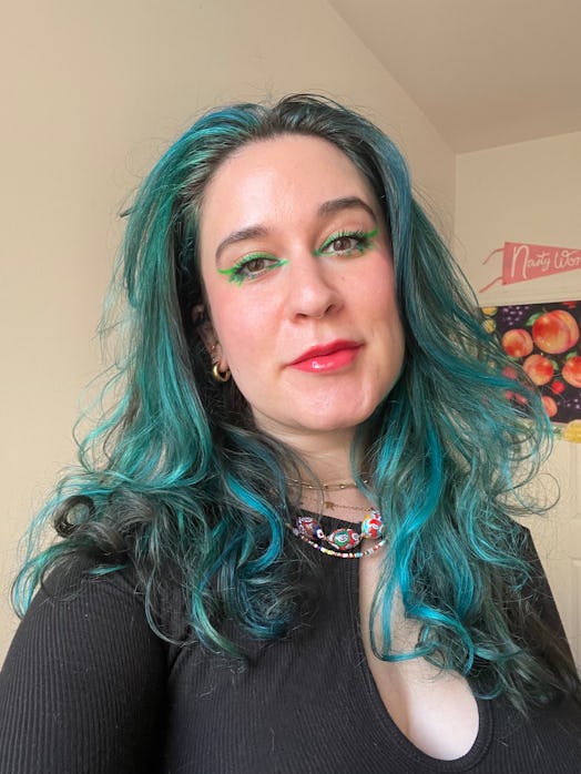 Woman with blue hair, green eyeliner, and glowing skin