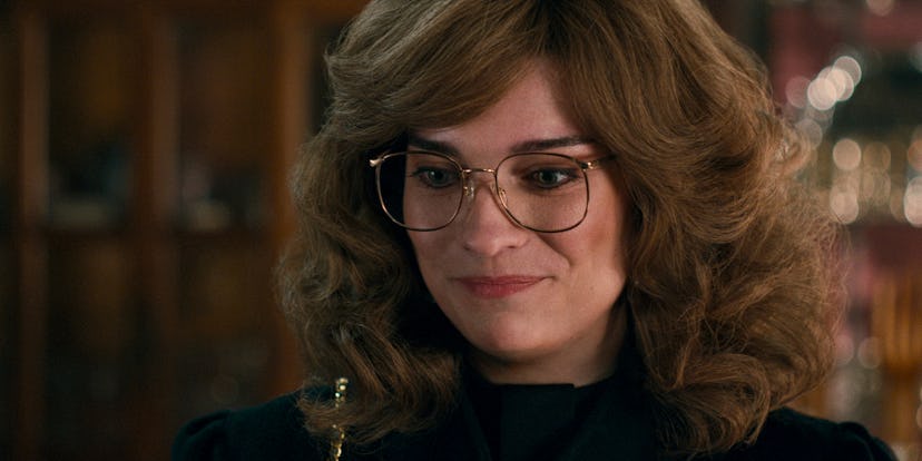 A closeup of Annie Murphy with curls and glasses looking down 