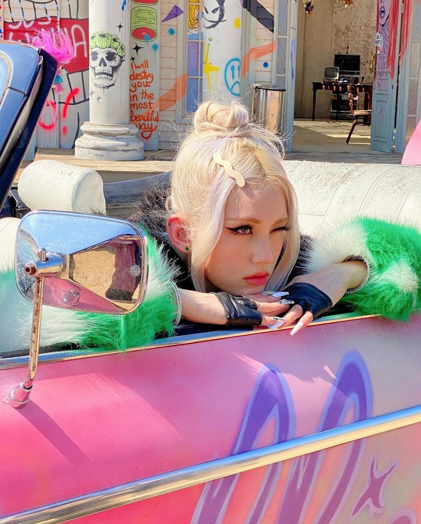 K-pop star with blonde hair in a pink car