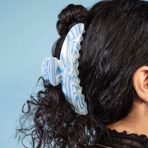 Woman with her curly hair up in a clue marbled Chunks claw clip