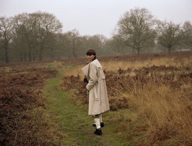 A model wears a khaki trench coat in a misty field