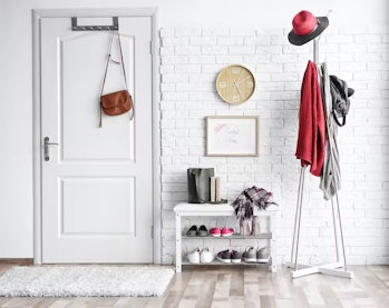 photo of an entryway with a small shelf, a coatrack, and a purse hanging over the door