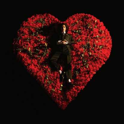 Conan Gray lays on a heart-shaped bed of roses in a black suit for his "Superache" album cover.