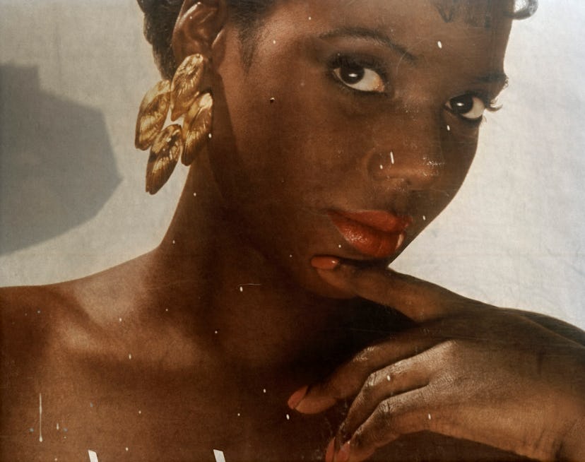 A woman wearing chunky gold earrings in an artwork by Deana Lawson 