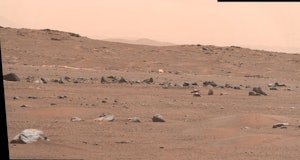The parachute of the Perseverance rover lies on the Martian regolith in the distance.