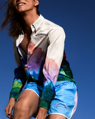 A girl in blue shorts and a colorful button-down shirt by Fiorucci.