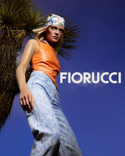 A girl wearing loose jeans and an orange top next to the name Fiorucci 