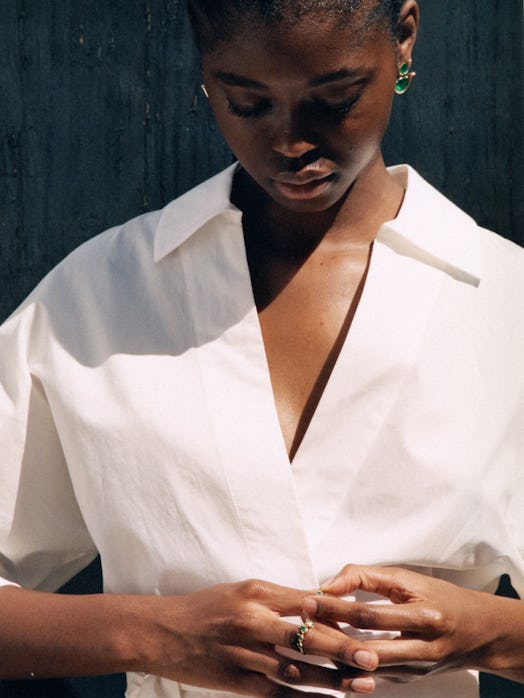  A model wearing a plain white collared shirt and green earrings and ring from Fernando Jorge’s Flam...