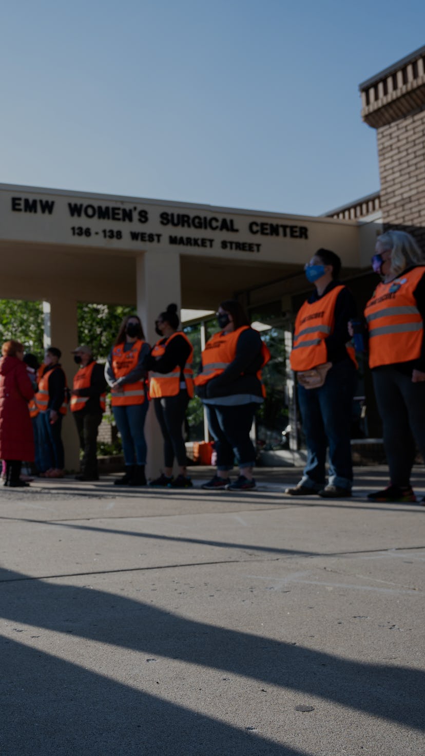 A pro-life demonstrator prostrates before a line of volunteer clinic escorts in front of the EMW Wo...