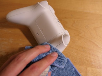 Wiping an Xbox controller with a microfiber cloth.