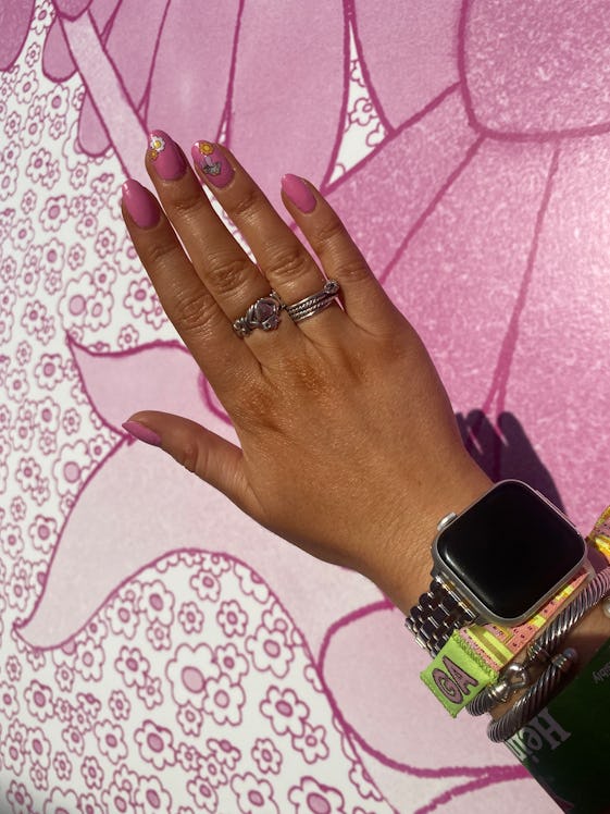A pink manicure complete with Pleasing mushroom and flower decals is posed in front of a floral wall...