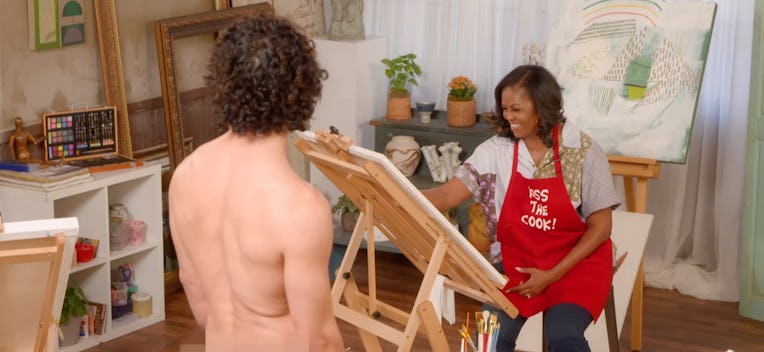 Michelle Obama painting on a canvas while a nude male model sits in front of her.