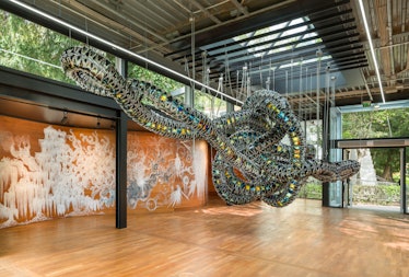 a snake-like sculpture suspended from the ceiling of a modernist pavilion