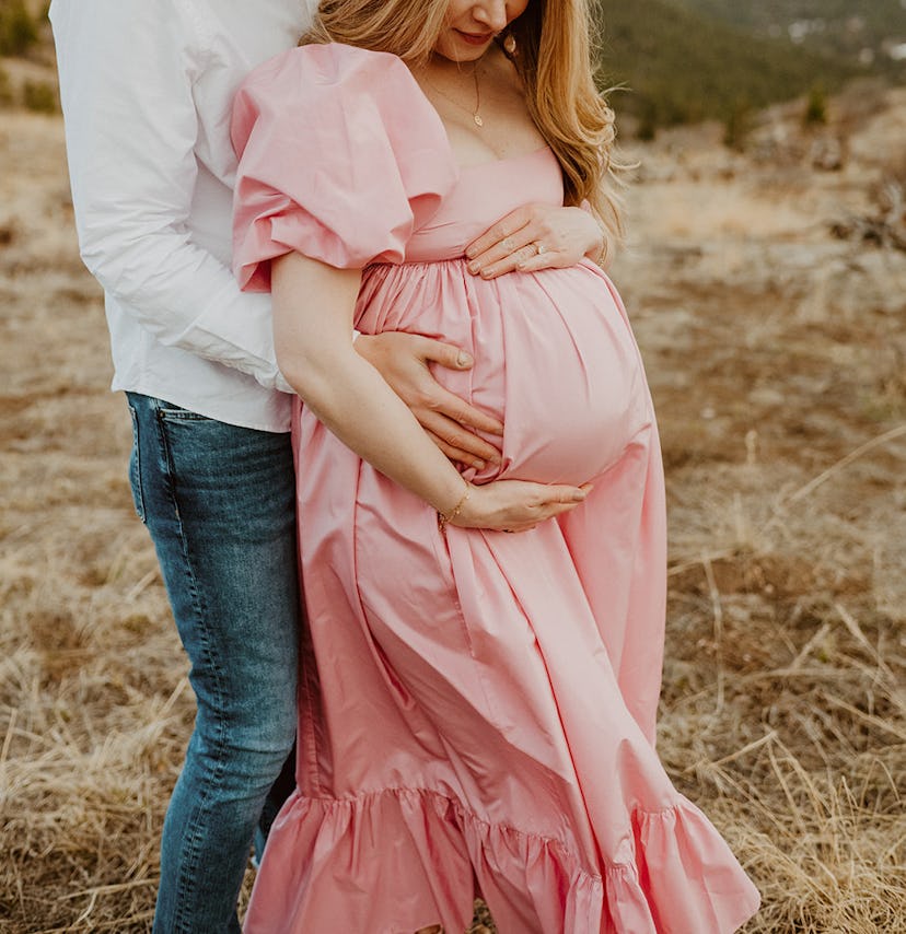 Laura with her husband, wearing a Doen dress at eight months pregnant 