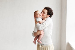 woman holding baby wearing onesie in her arms