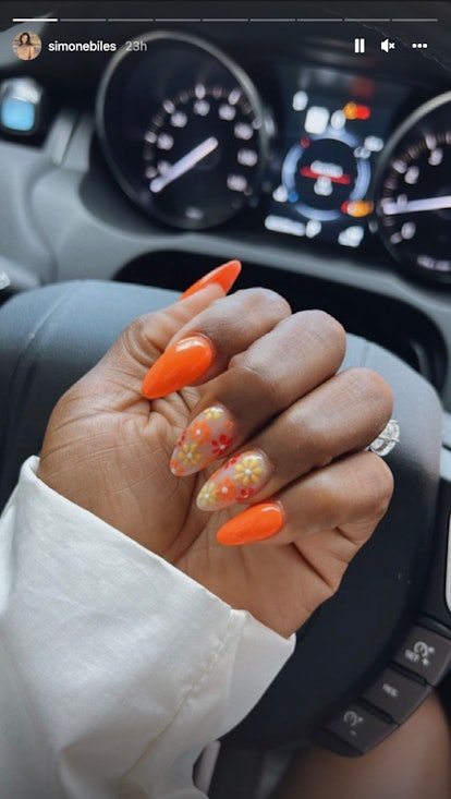 Simone Biles shows off a red, orange, and yellow floral spring manicure