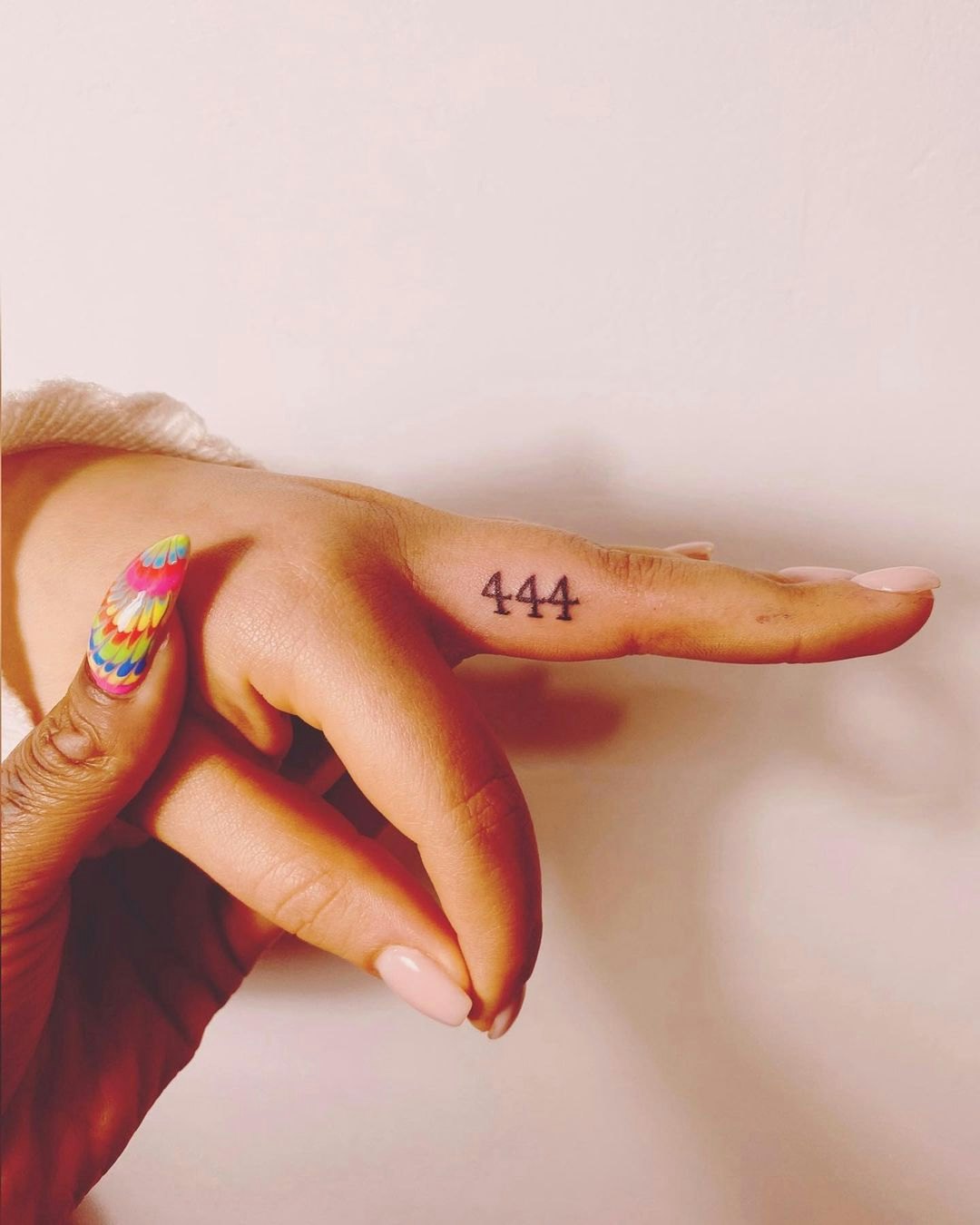 Number 444 tattoo located on the thumb