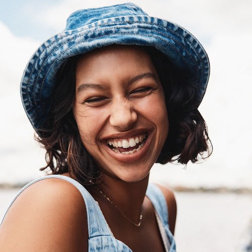 Girl smiling while wearing a sustainable denim top with a matching hat