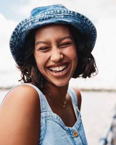 Girl smiling while wearing a sustainable denim top with a matching hat